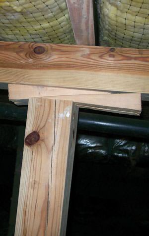 Wedges of wood used as shimming for crawl space floor joist bracing