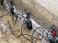 Using foundation push piers to lift a foundation during a repair in Orem.