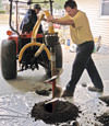 Digging a hole in the garage floor to make room for a wall anchor installation in Spanish Fork, Utah