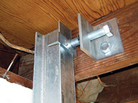 Securing the i-beam system to the top of the floor joist in a foundation wall repair in Sandy.