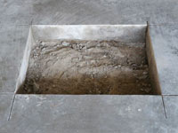 Creating the hole in the garage slab floor during the wall anchor installation in South Jordan.
