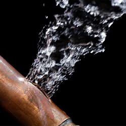 A bursting copper pipe in Provo, with water gushing out.