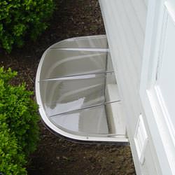 A vinyl basement window and covered window well in Magna